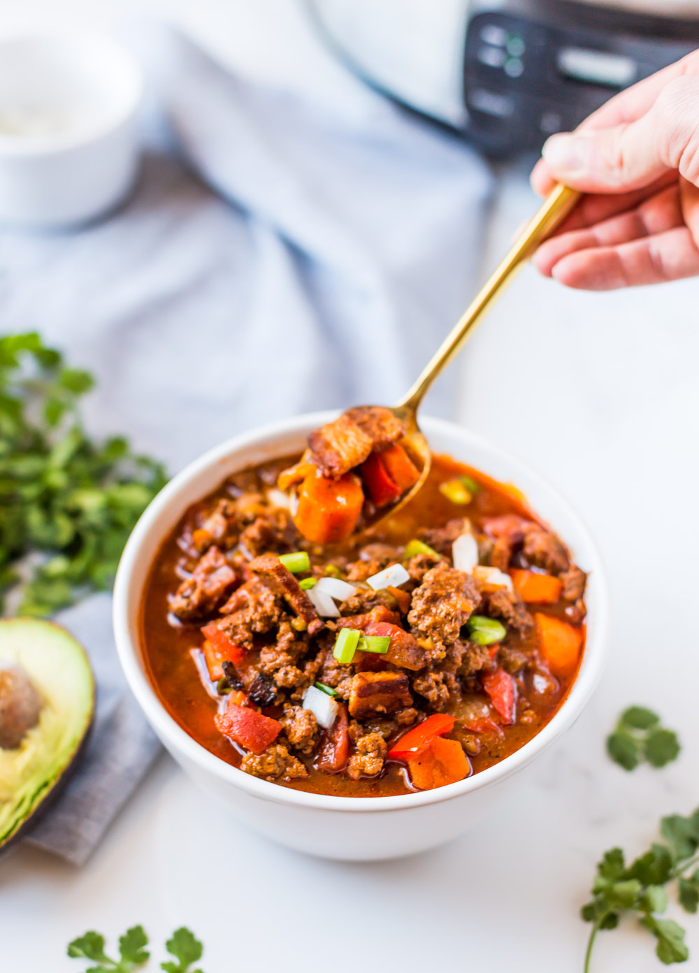bowl of paleo chili with gold spoon scooping chili out of bowl
