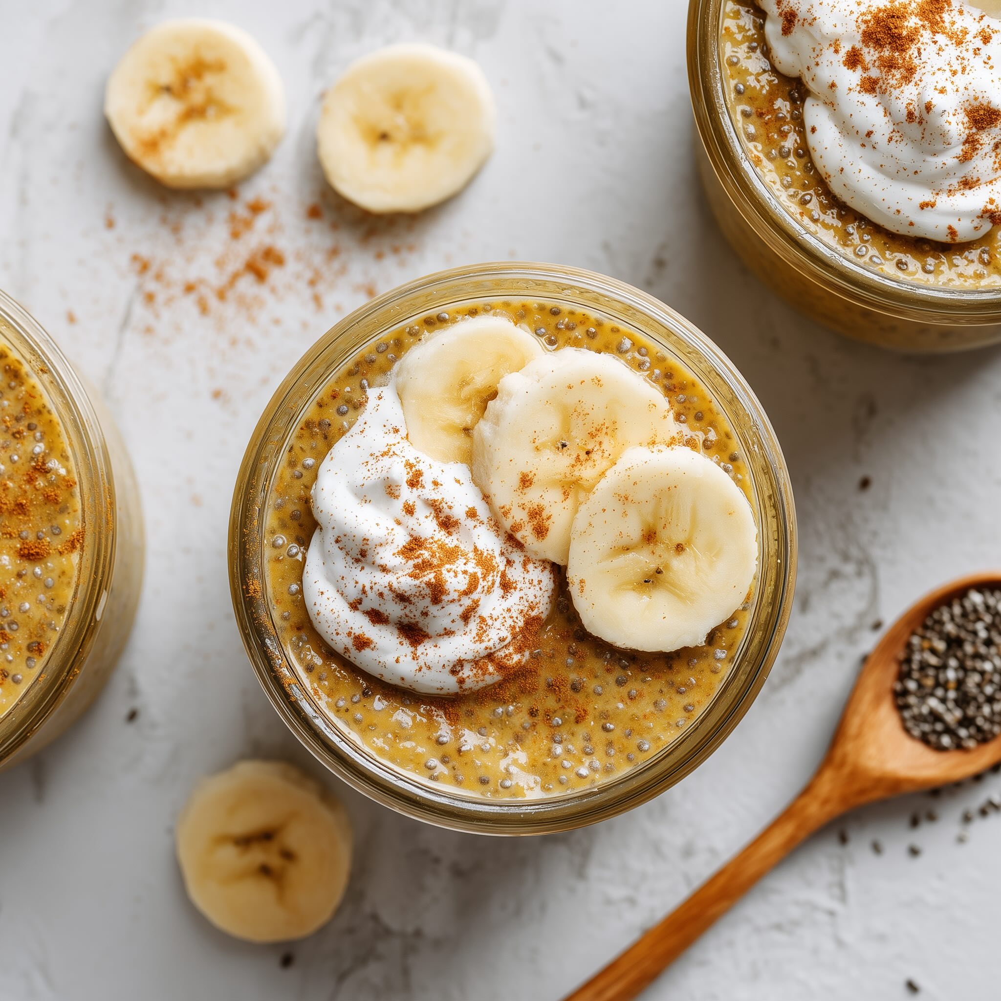 Banana coconut milk chia pudding topped with fresh banana slices and coconut cream in a glass jar