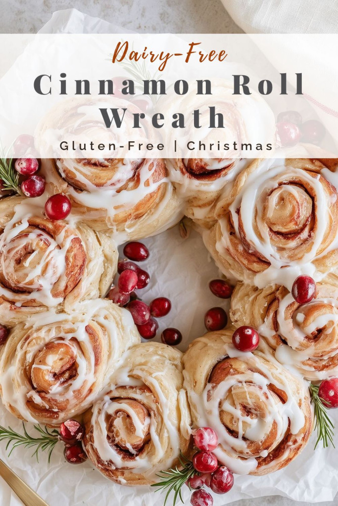 pinterest-ready image of glazed cinnamon roll wreath topped with cranberries and rosemary on parchment paper